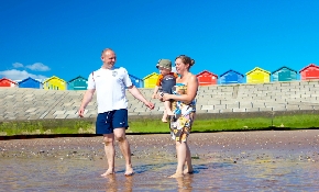 Family on beach with beach huts behind